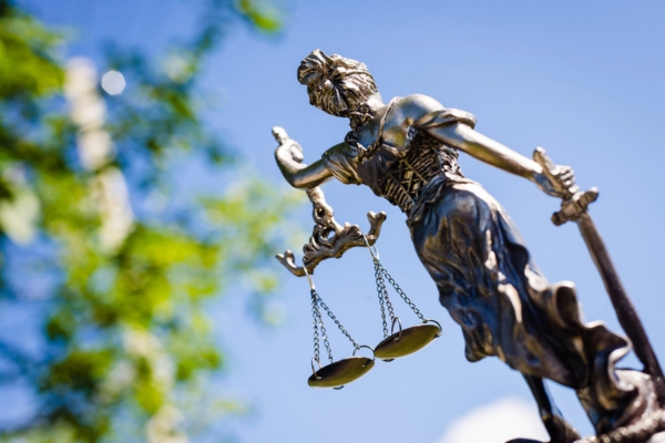 justice scale with blue sky and tree in the background depicting legal and environmental impact