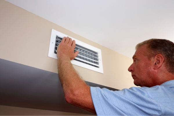 homeowner checking air vent depicting overheating blower motor