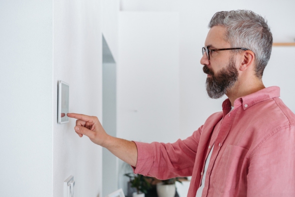 man adjusting home thermostat for energy efficiency