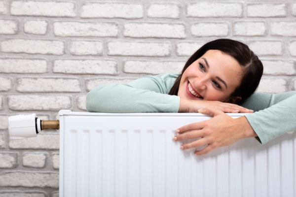 woman smiling while leaning on home radiator