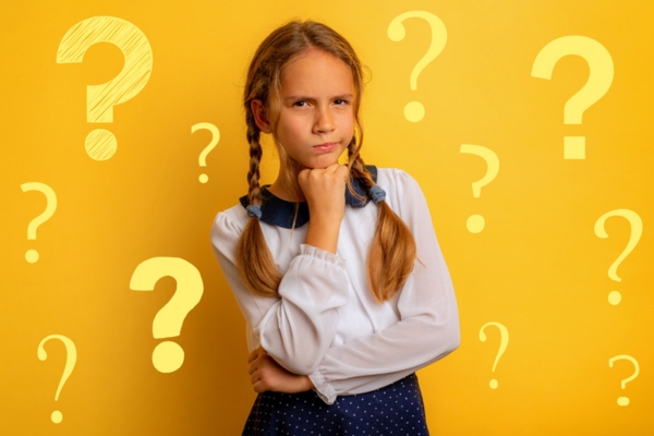 young girl thinking and standing in front of a yellow wall with question mark doodles depicting oil burner cleaning FAQs