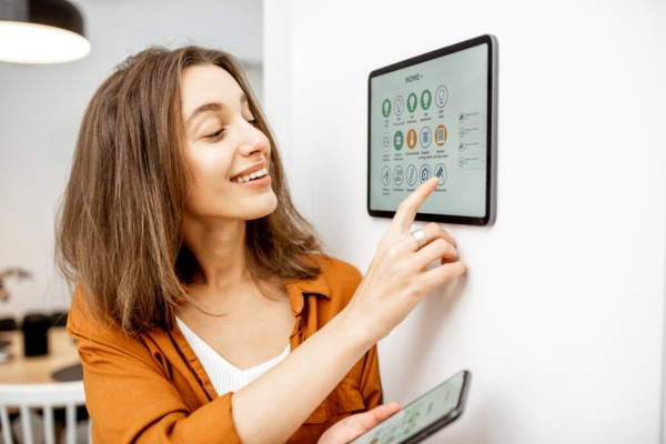 woman controlling smart programmable thermostat from home tablet and mobile phone